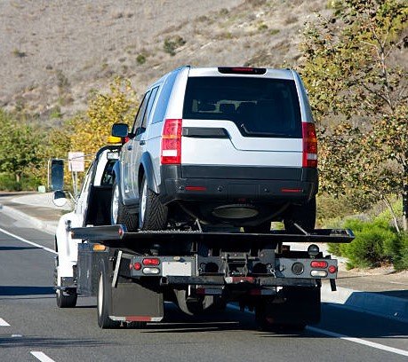 a tow truck towing a silver suv.